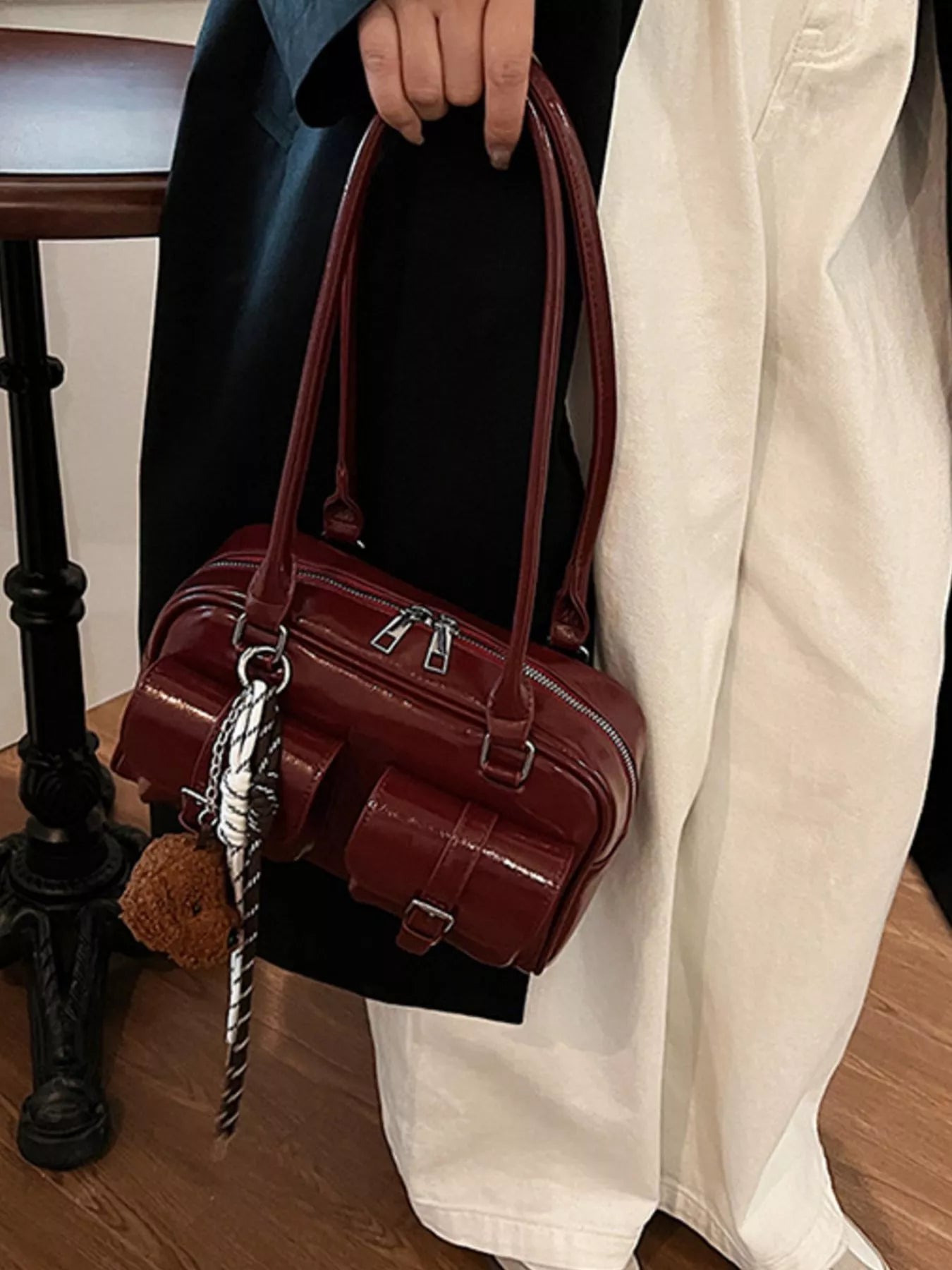Deep red mini shoulder bag with dual top handles, front buckled flap, hanging chain