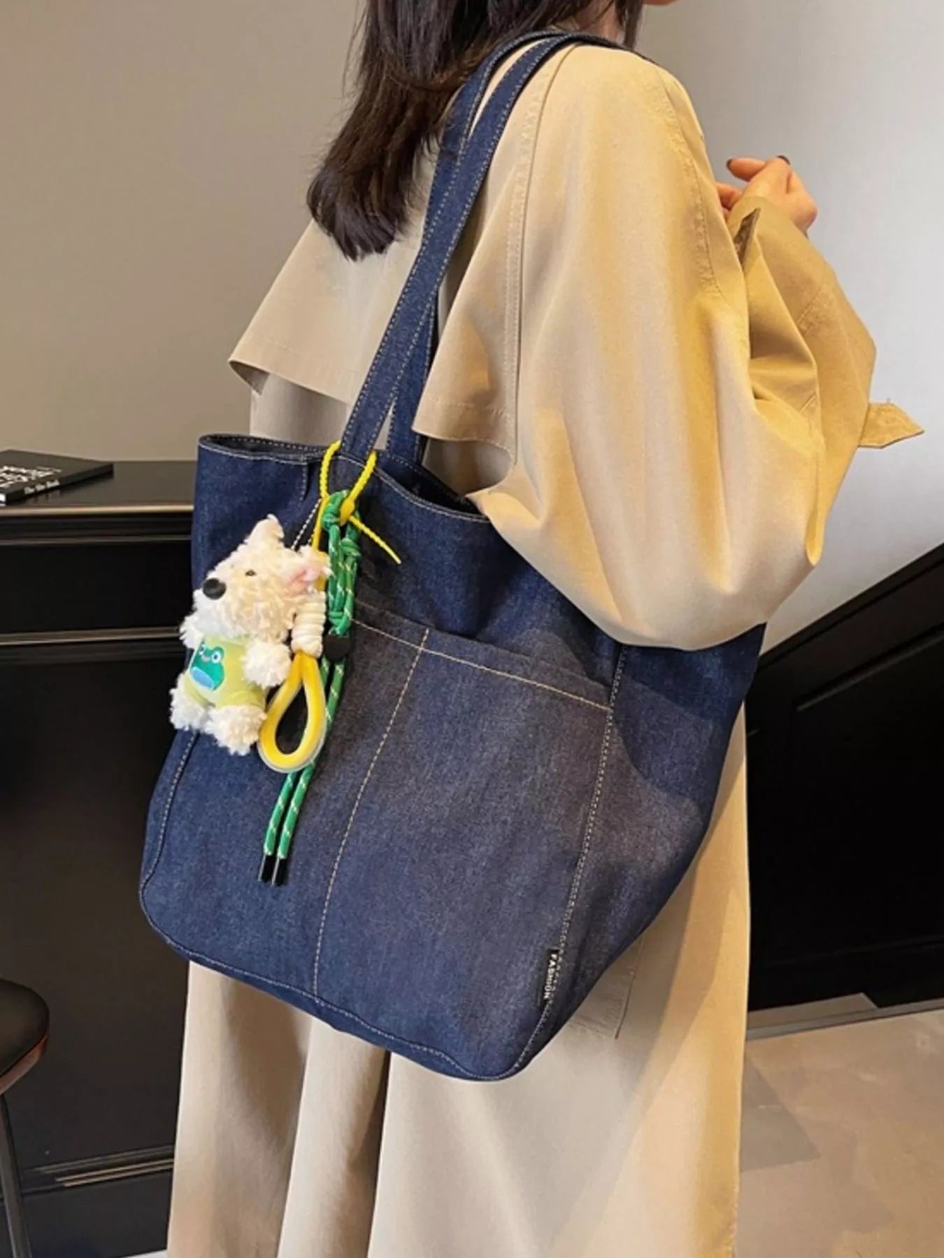 Dark navy denim tote with long straps and hanging plush charm