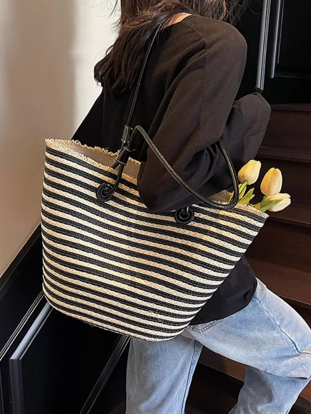 Striped woven straw tote bag with black handles and stitched striped body