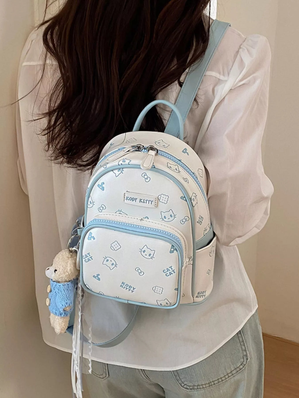 Pastel blue cat cartoon backpack with rounded top, double zippers, and plush keychain