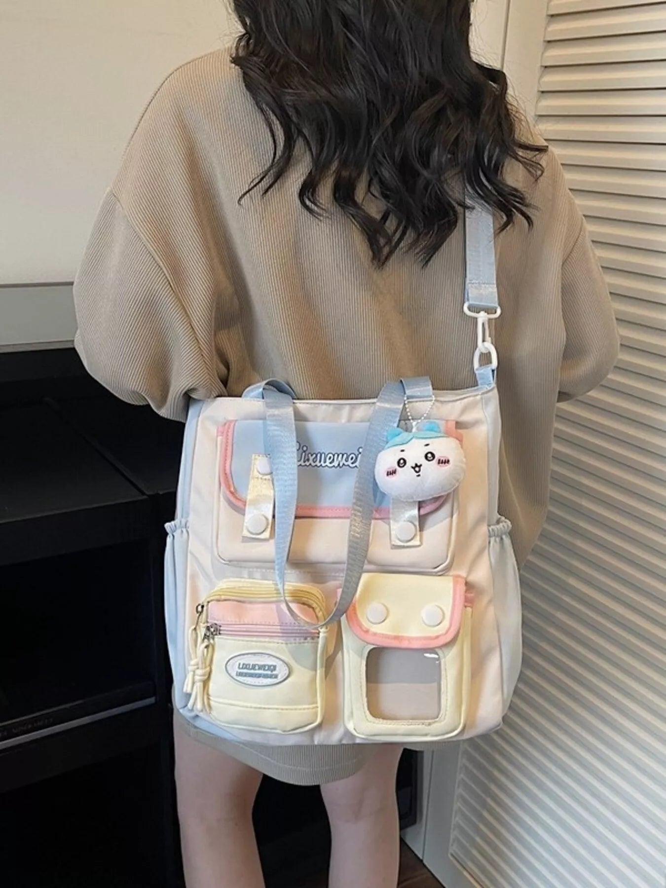 Multi-pocket shoulder bag worn crossbody, pastel blue strap and front pouch compartments