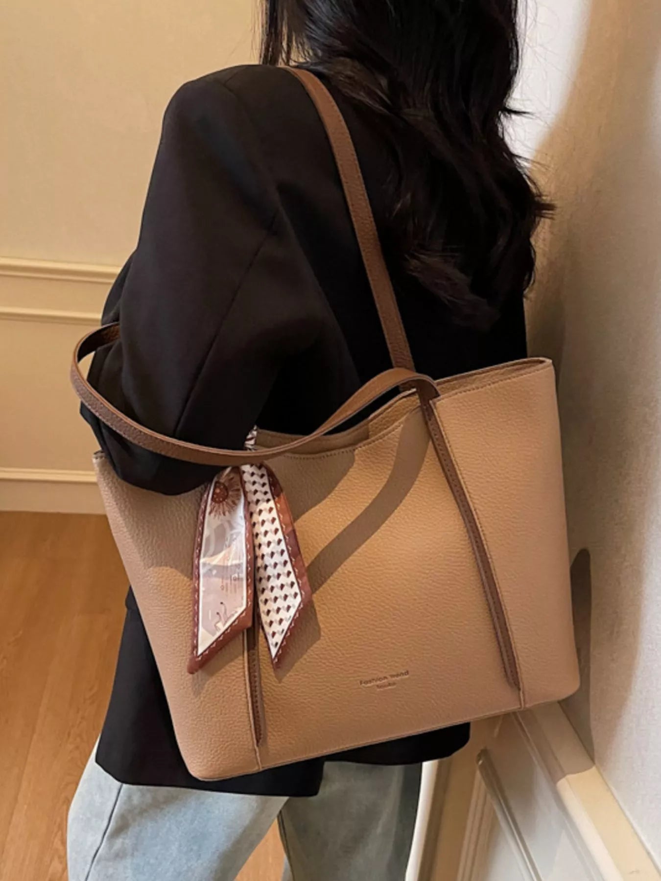 Person carrying khaki PU leather tote with long shoulder straps and front scarf
