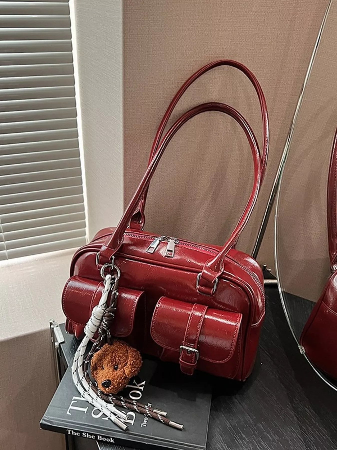 Deep red glossy shoulder bag with front buckled flap, teddy keychain charm and chain strap