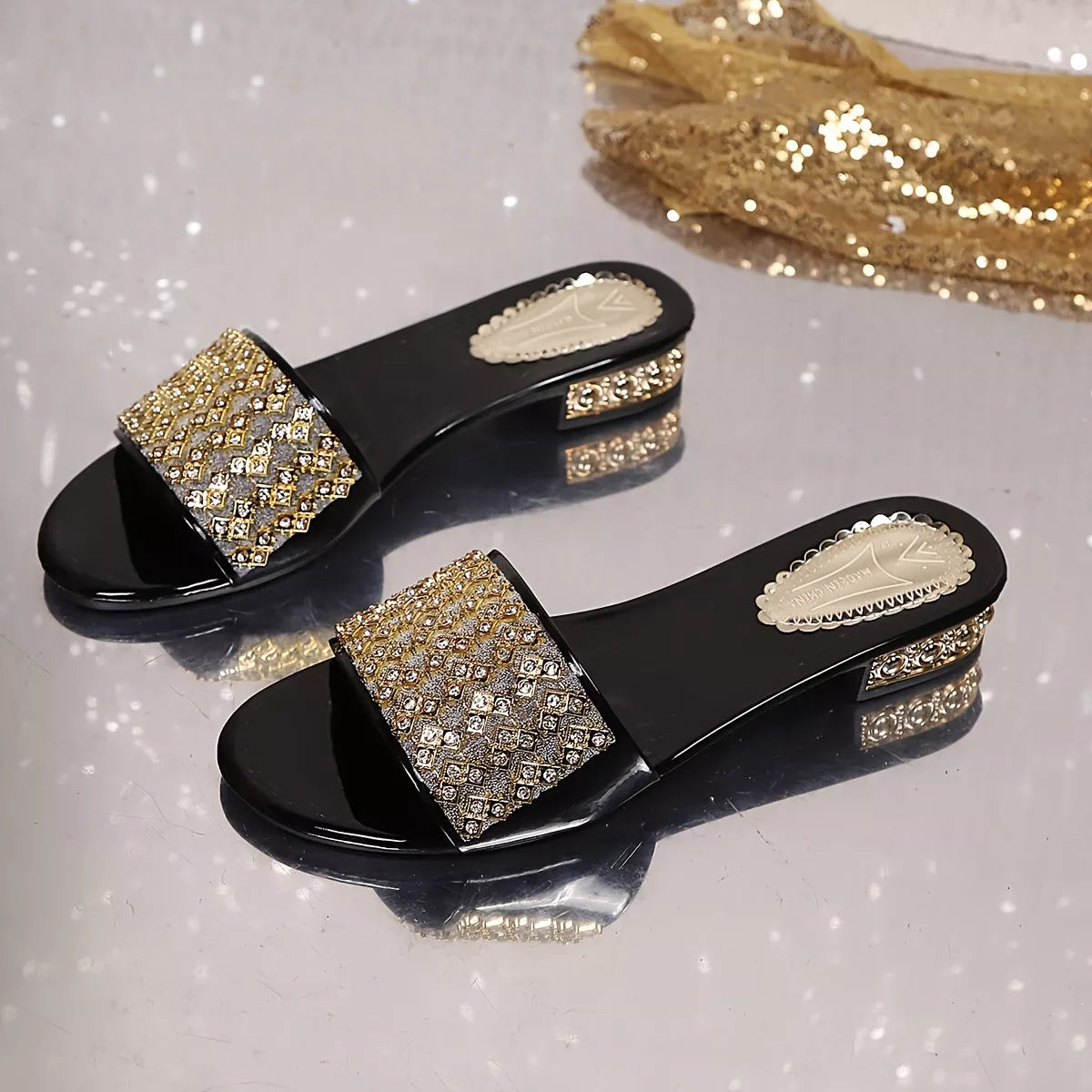 Pair of gold open-toe block heels with jeweled straps and black heel blocks