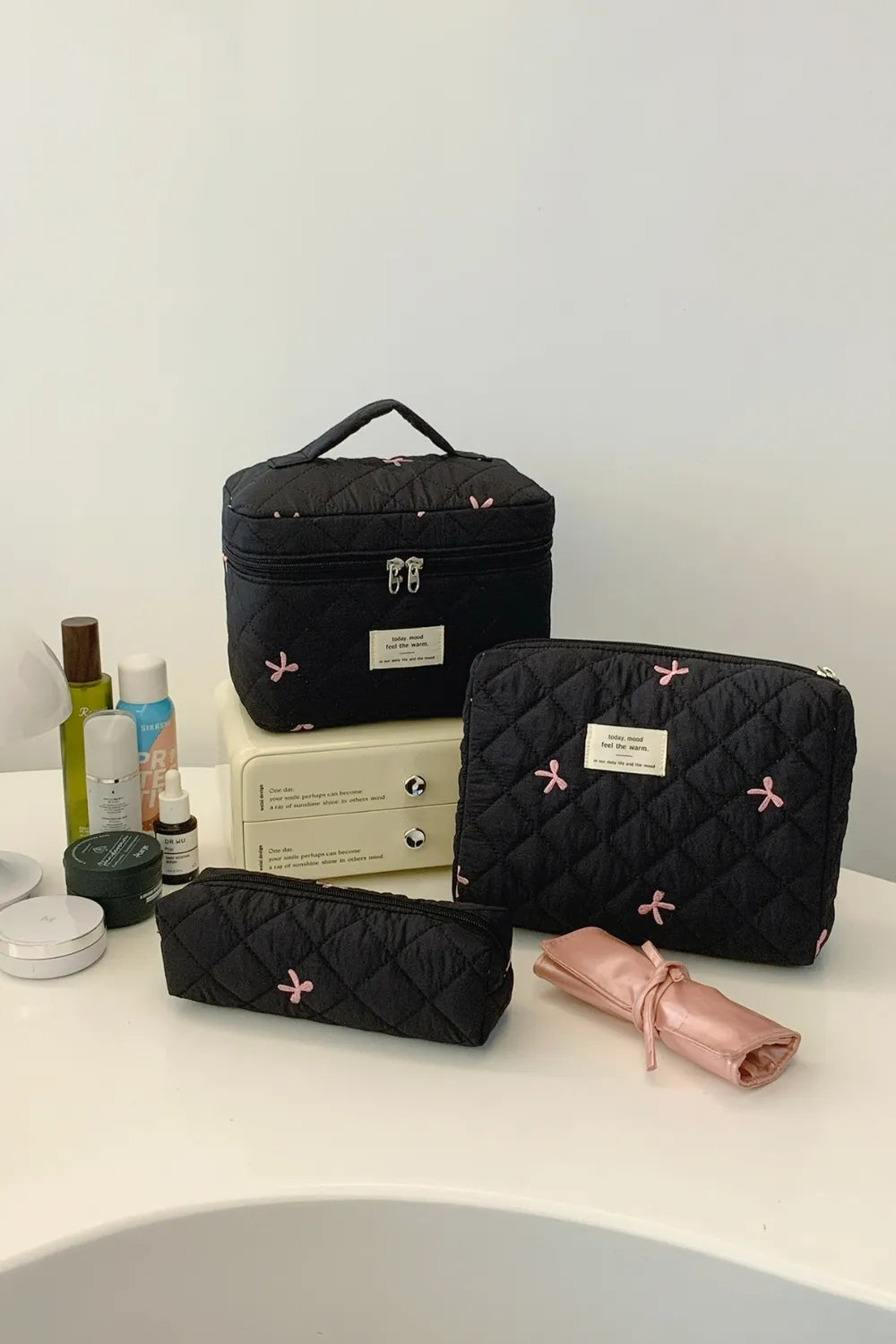 Black quilted 3-piece storage bag set with bow pattern and pink-zip pouch roll.