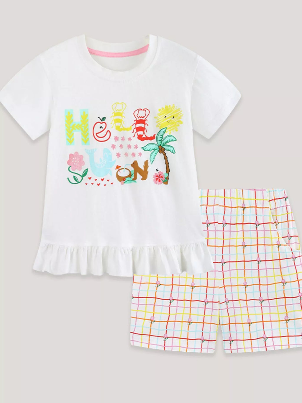 White graphic T-shirt with ruffle hem and multicolor plaid shorts set, flat lay