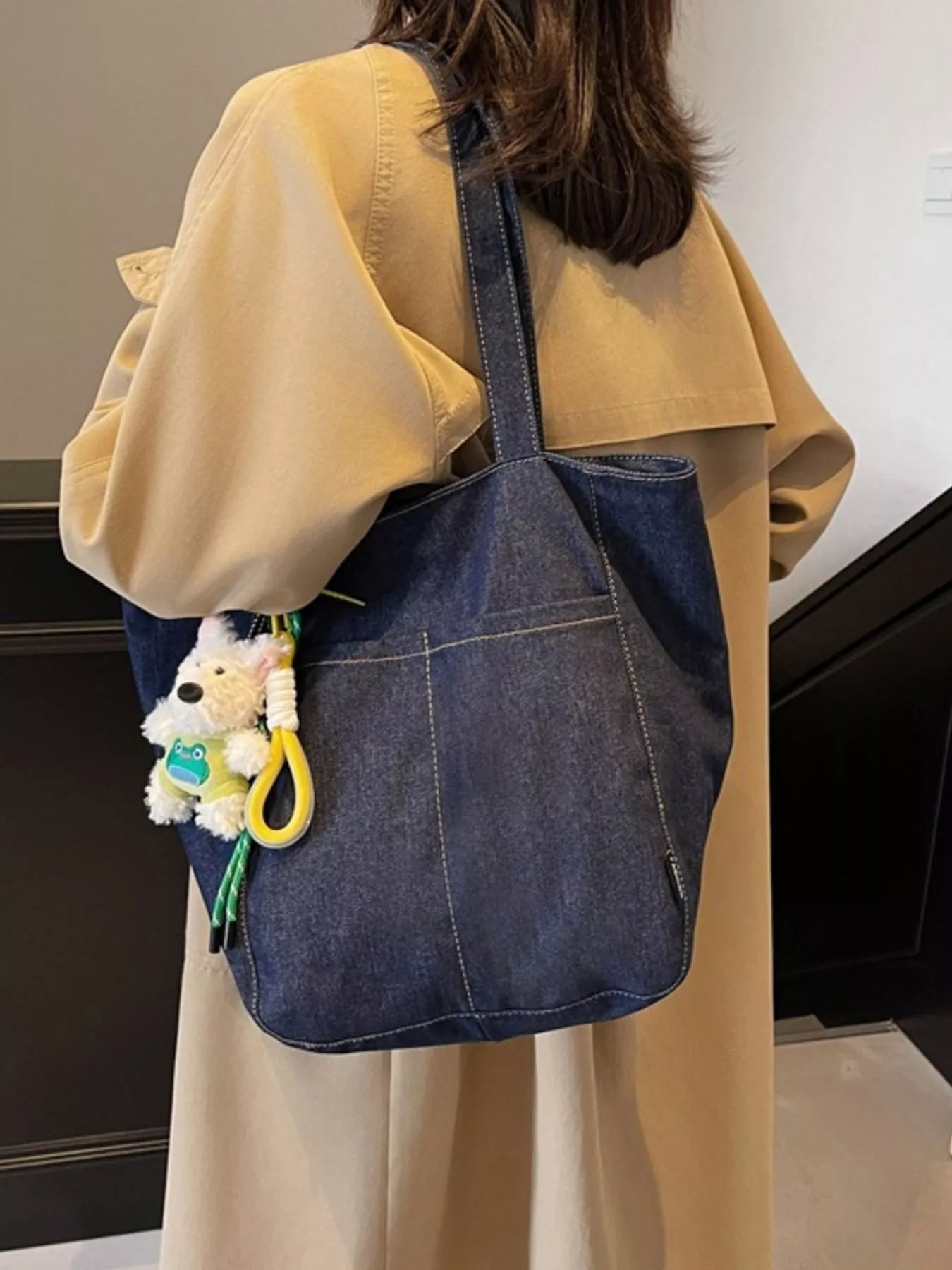 Navy denim shoulder tote with long straps and hanging plush charm on front