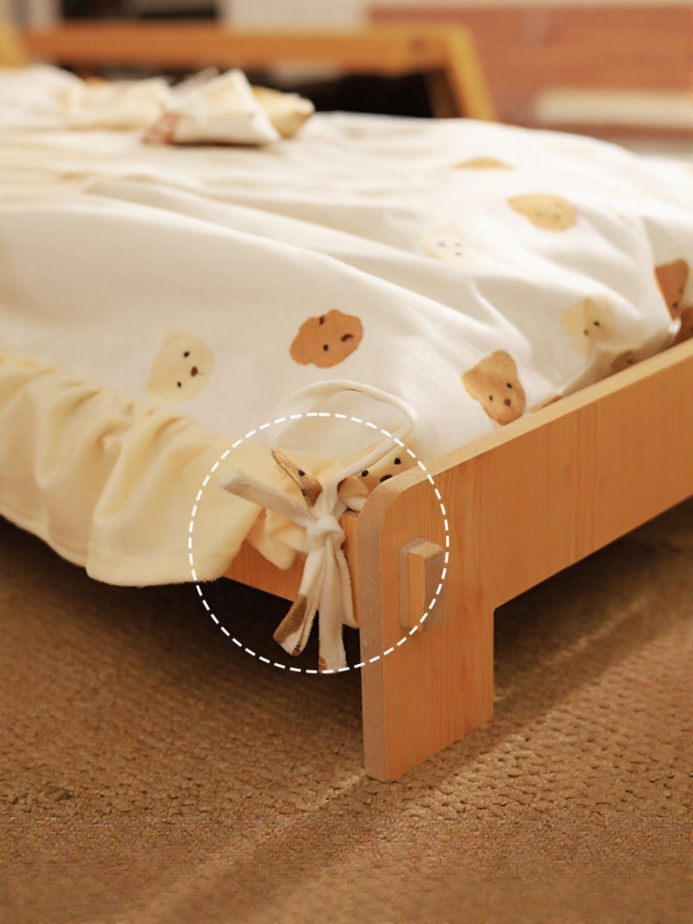 Wooden pet bed corner showing bear-pattern blanket tie and elastic gathered edge.