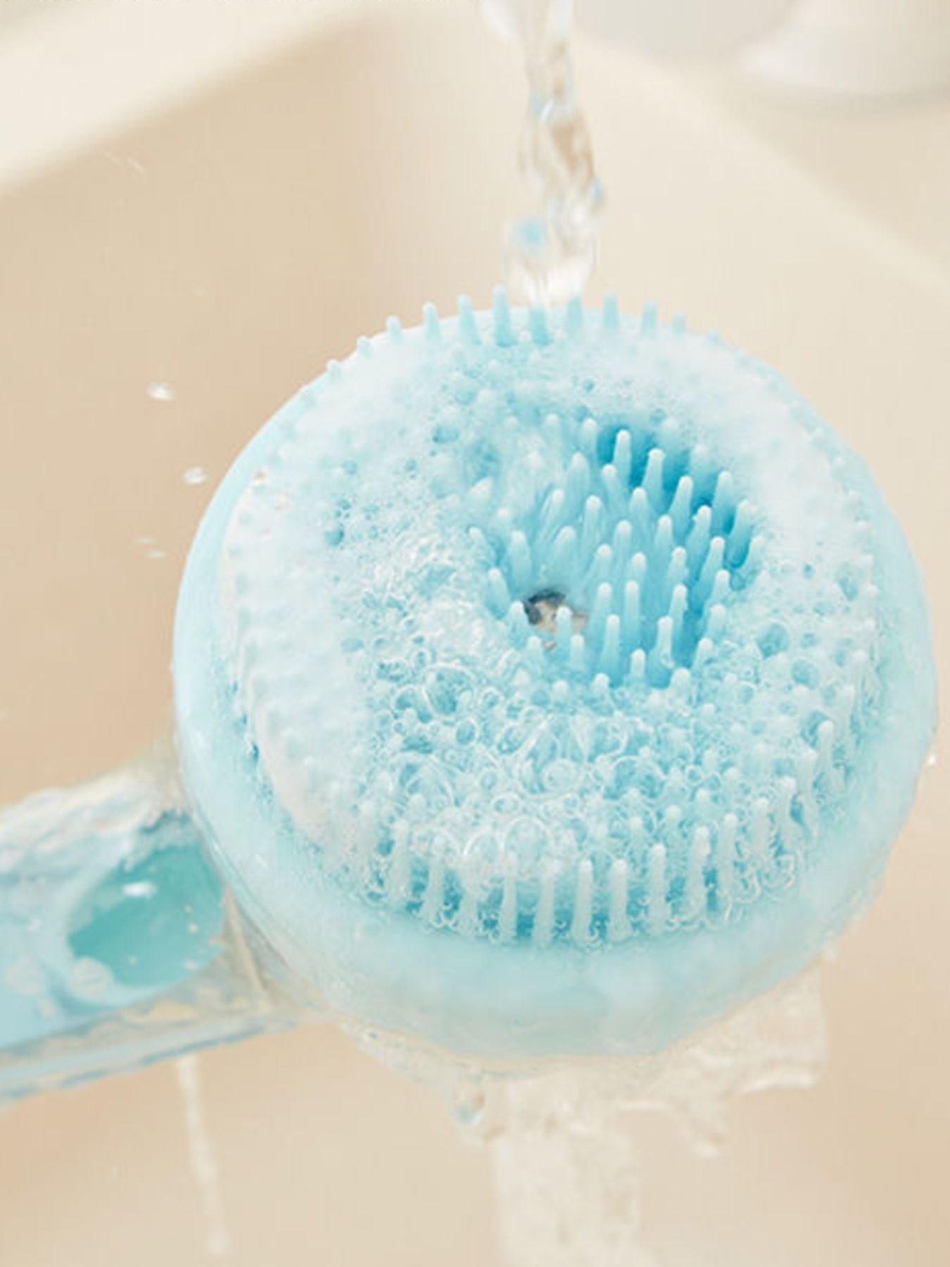 Soft Pet Shower Brush head in light blue with soap bubbles and water suds