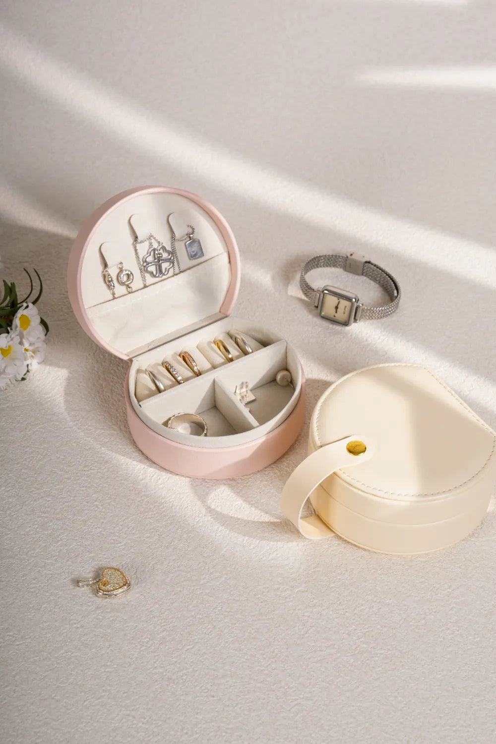 Blush pink round travel jewelry box with compartments and jewelry pieces inside