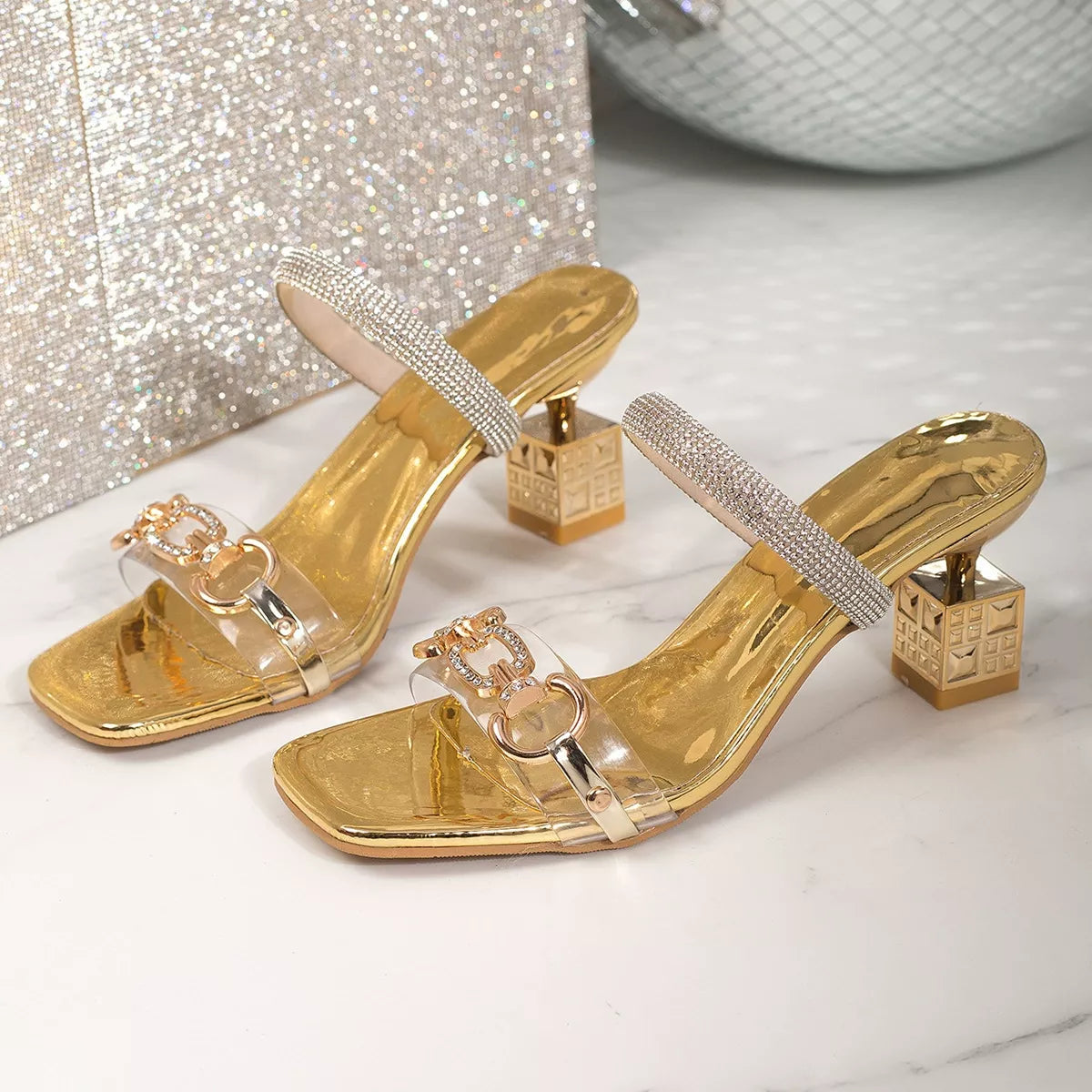 Gold open-toe heeled sandals with rhinestone band and clear strap with ring buckle