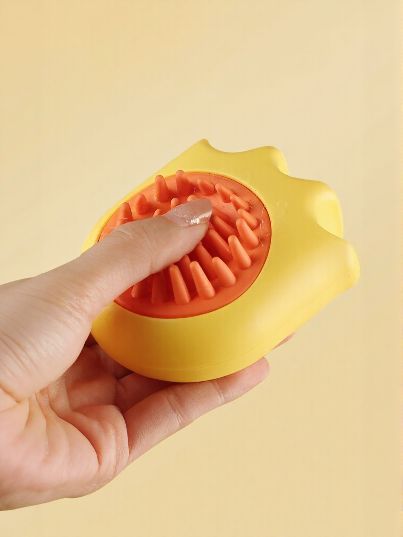 Yellow pet shower brush with orange bristle side, being held and ready for grooming