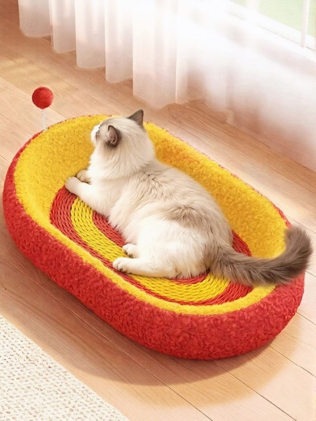 Oval cat scratching bed with red outer sides and yellow interior striped scratch surface