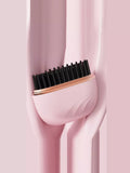 Portable hair straightening comb in blush pink with black heated teeth