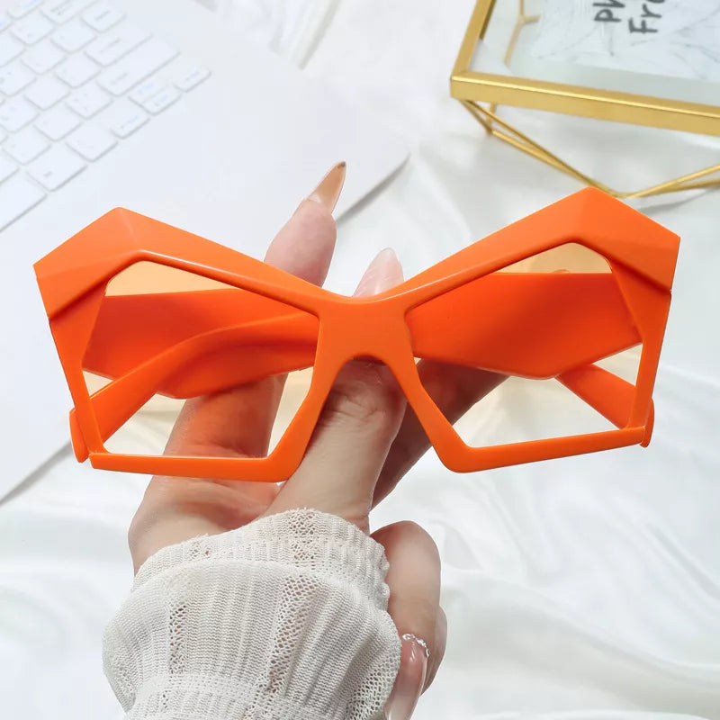 Orange geometric sunglasses frame held in hand, bold angular shapes