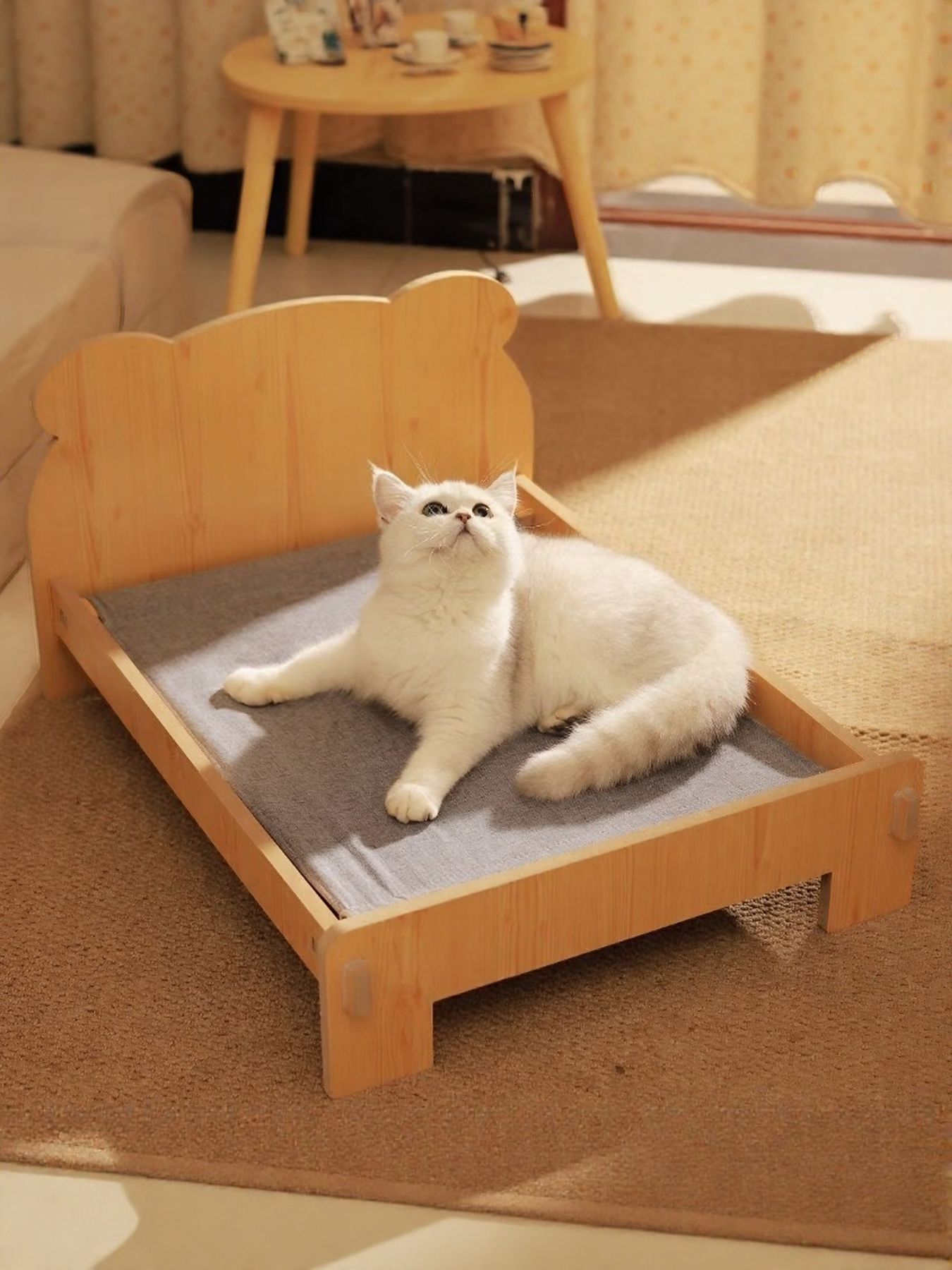 Wooden pet bed base with gray cushion, cat sitting inside with paws forward.