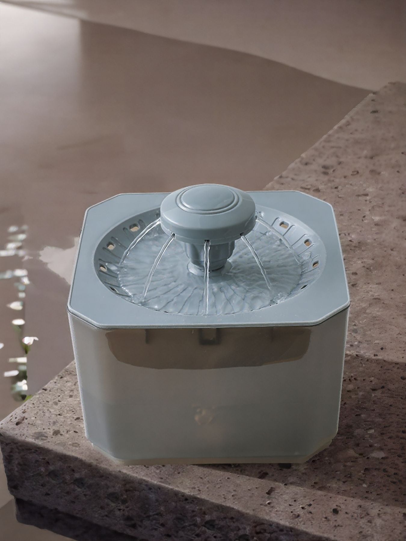Pet water fountain with gray nozzle, clear reservoir and steady water stream