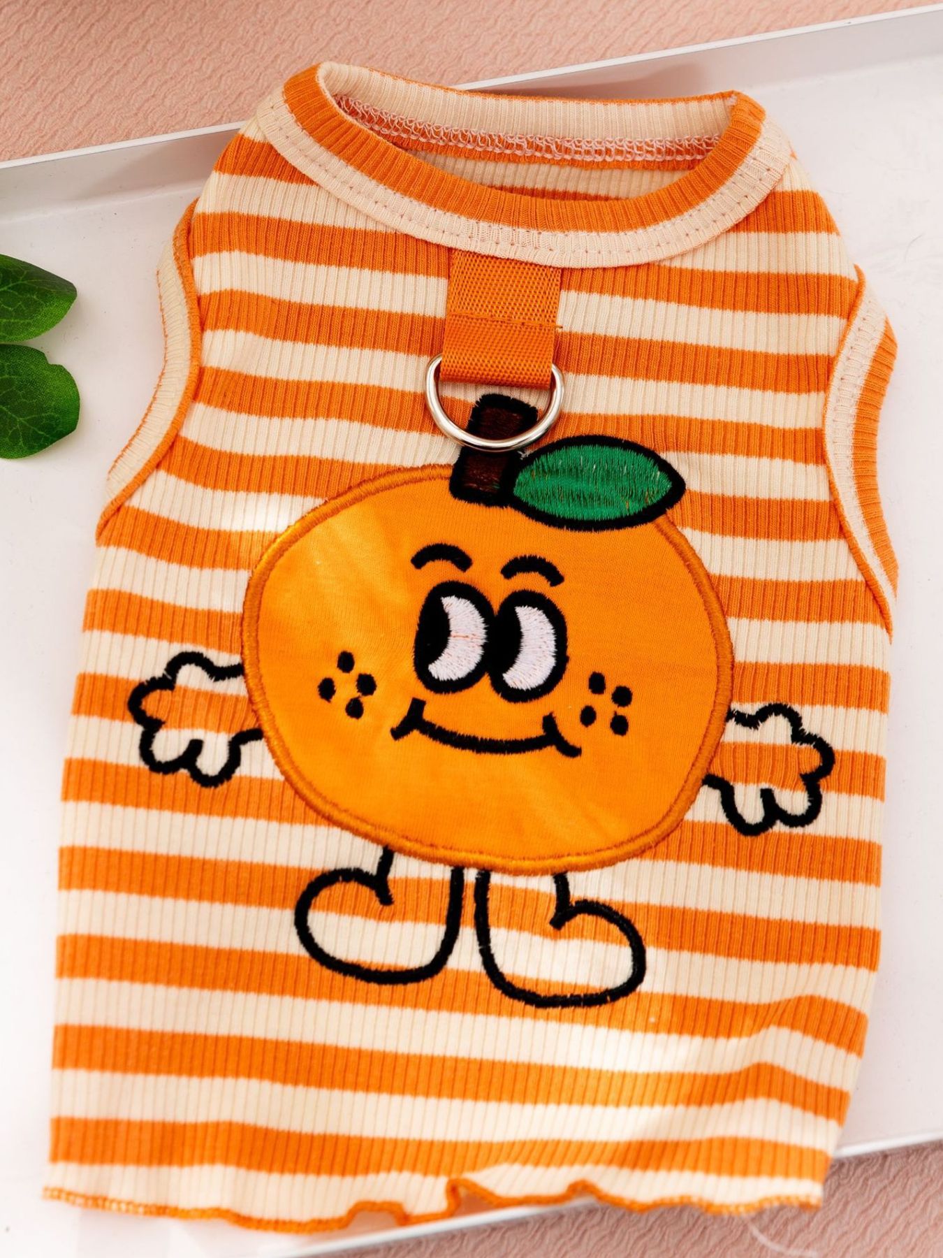 Orange striped pet tank with bear appliqué and metal collar ring, close-up