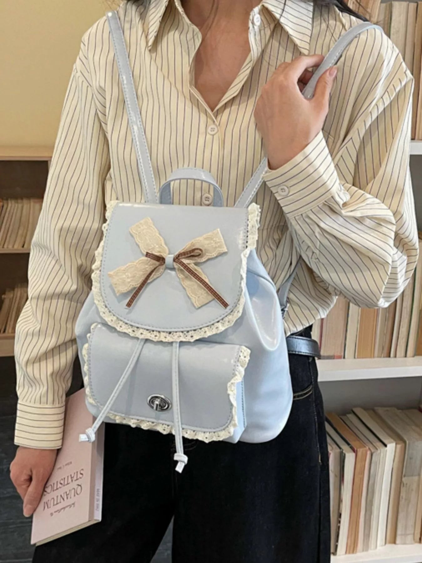 Light blue mini backpack with lace trim, bowknot accent, and front pocket panel