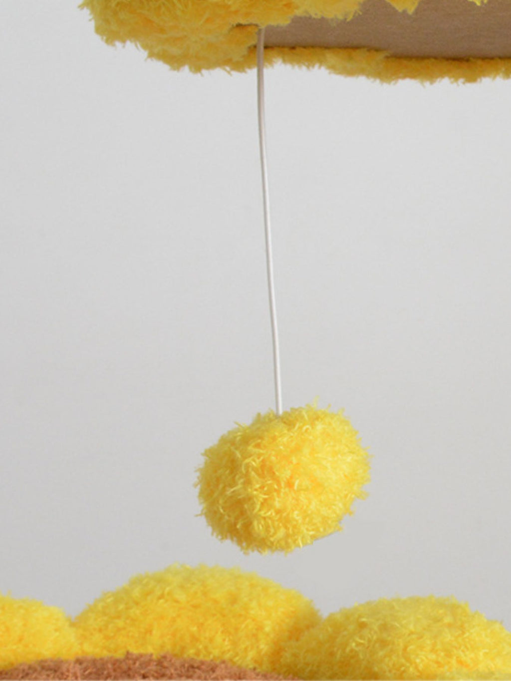 Juguete colgante amarillo tipo pompón sujeto a la parte superior