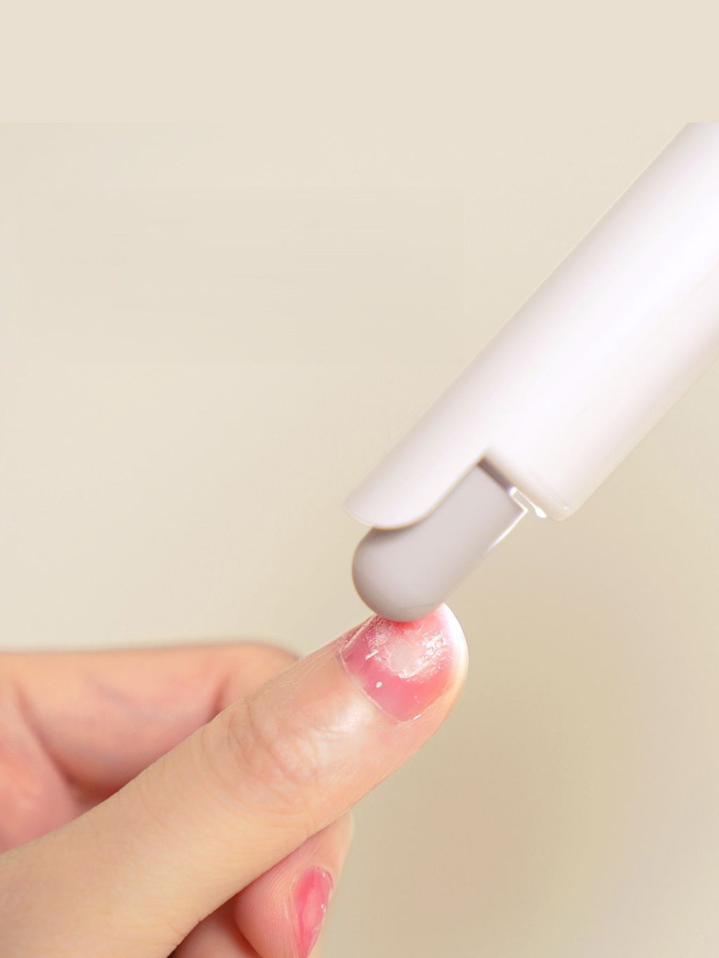 White nail buffer tip pressed to fingernail for buffing