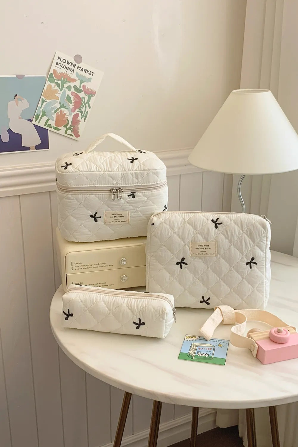 Beige quilted storage bag set with bow pattern; three zipped pouches with handles