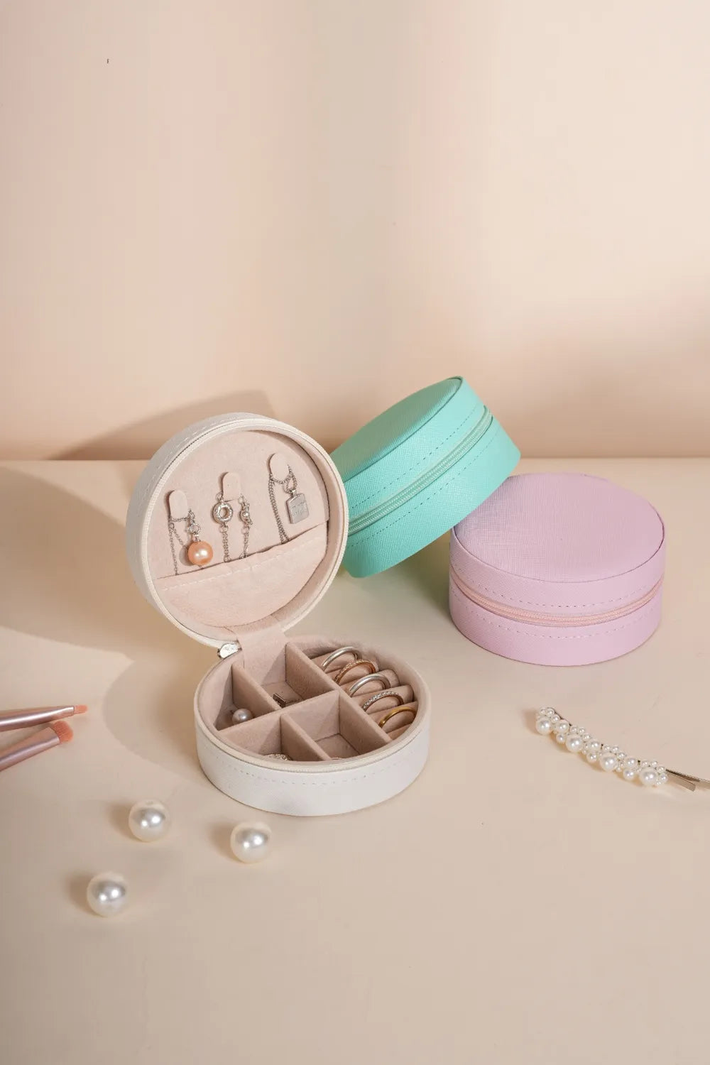 Open jewelry storage box with pastel lids (teal and blush pink) and ring compartments