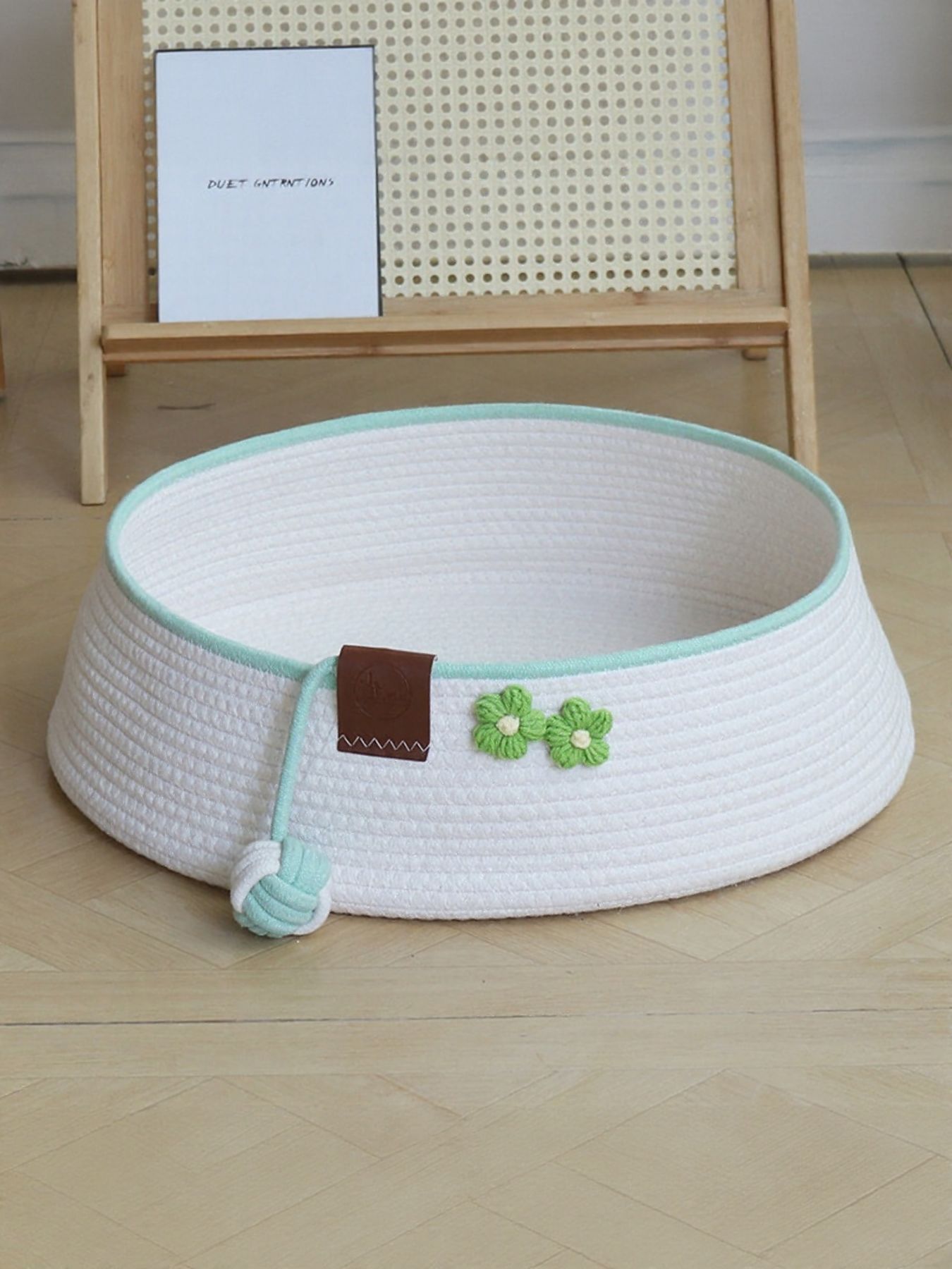 White woven pet nest with mint edge, green clover decoration, and plush rope toy