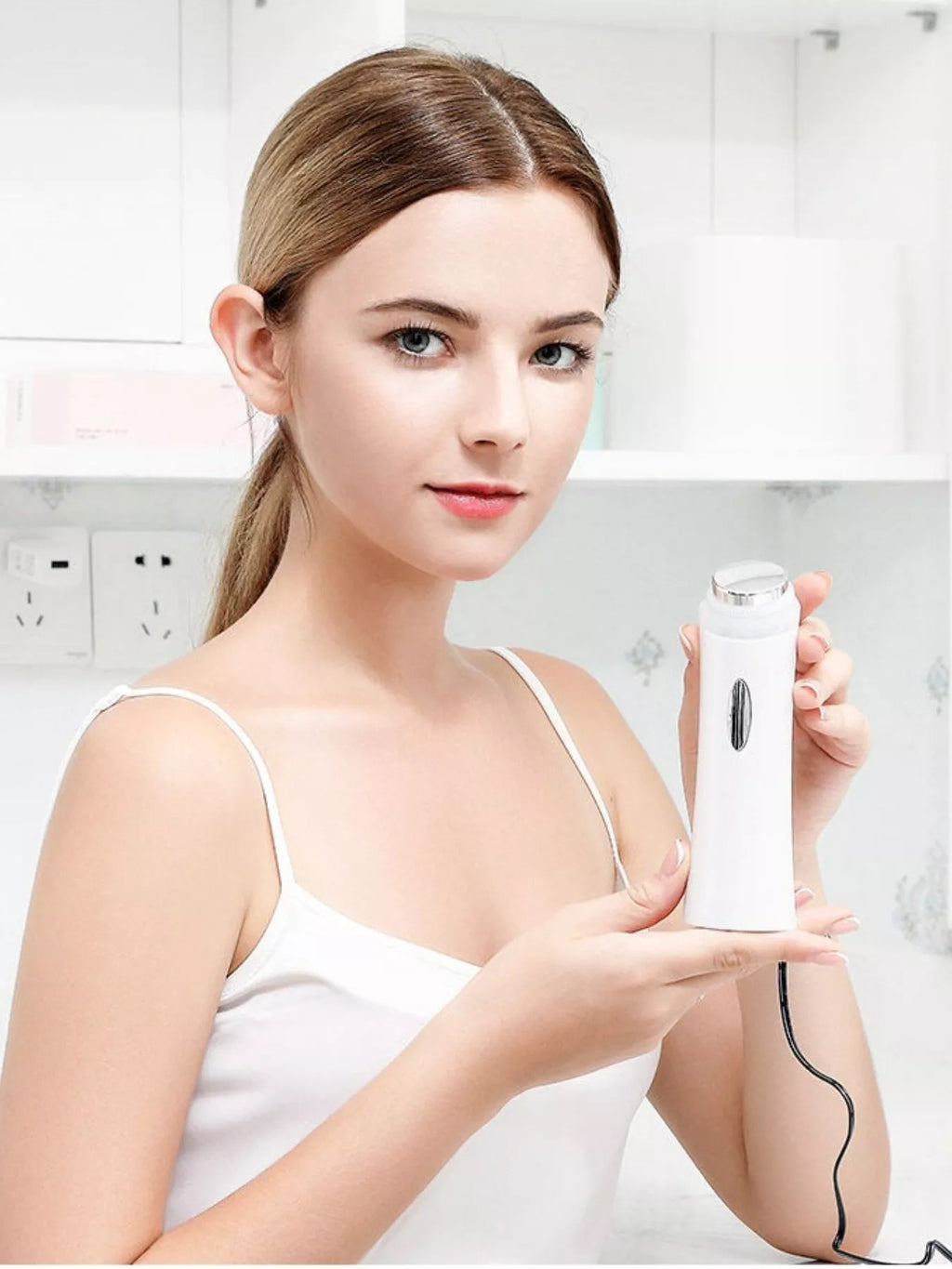 White facial skin tightening device held for facial use with cord connected
