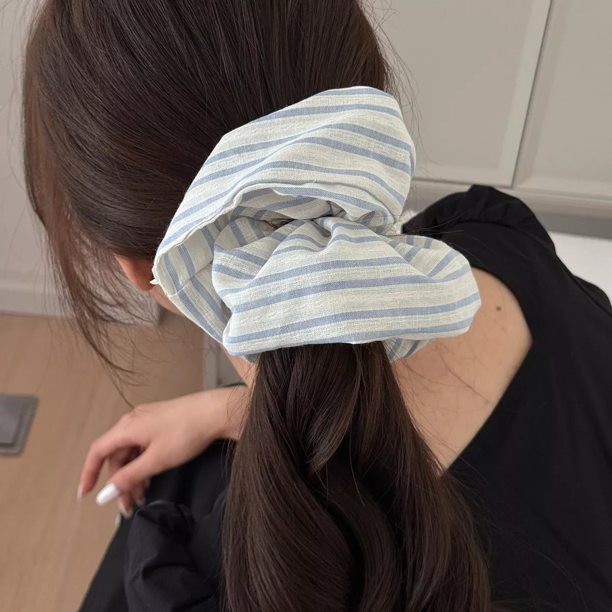 Light blue striped scrunchie worn in hair bun, tied bow style