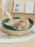 Woven pet nest with green cushioned interior and striped rim, cat resting inside