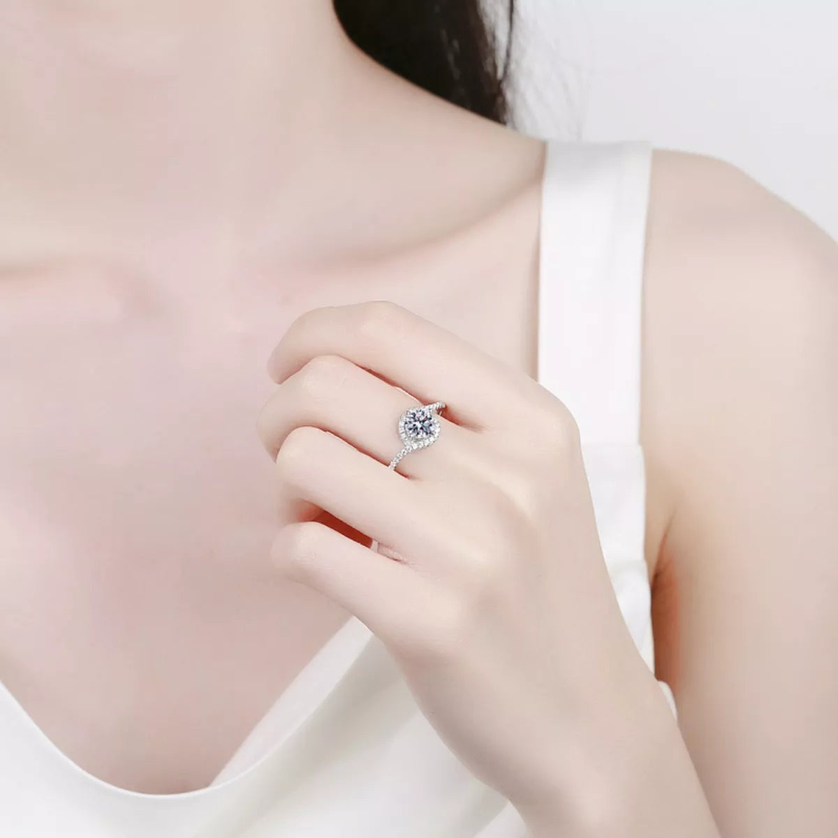 Silver moissanite halo ring on hand with round center stone and pavé detail