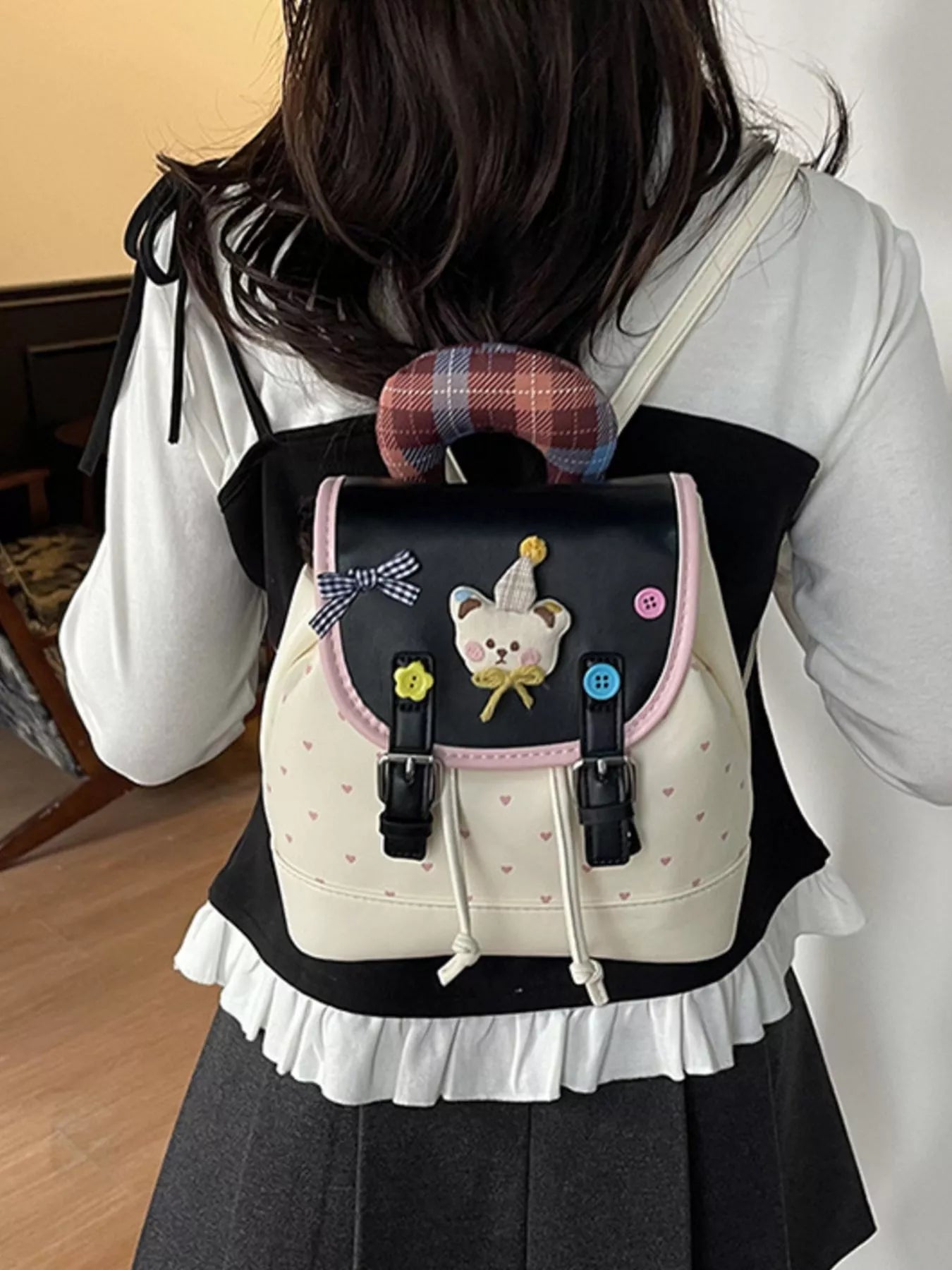 Beige backpack on model: front bear applique with buttons, pink trim and drawstring cords