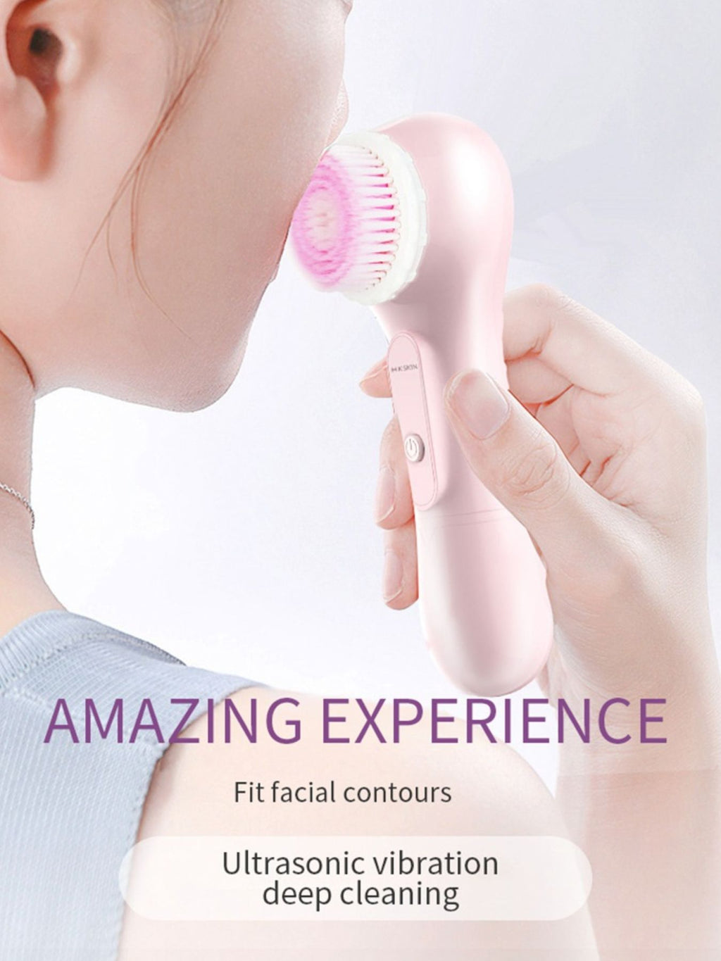 Pink facial cleansing brush with round bristle head touching cheek
