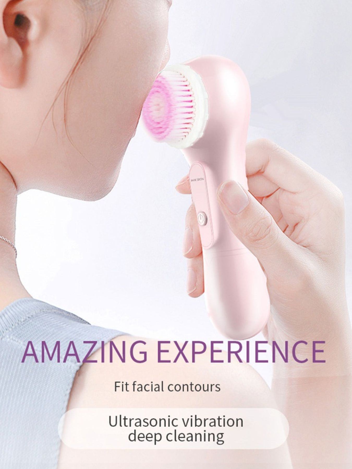 Pink facial cleansing brush with round bristle head touching cheek