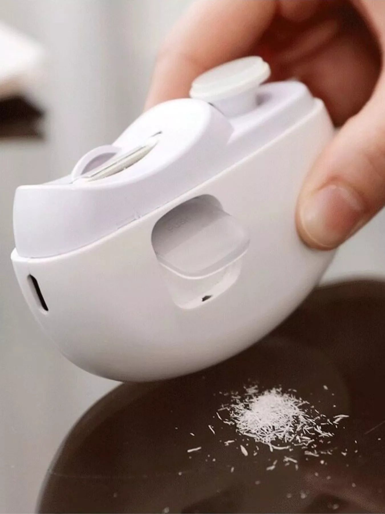 White electric nail buffer releasing nail dust onto surface
