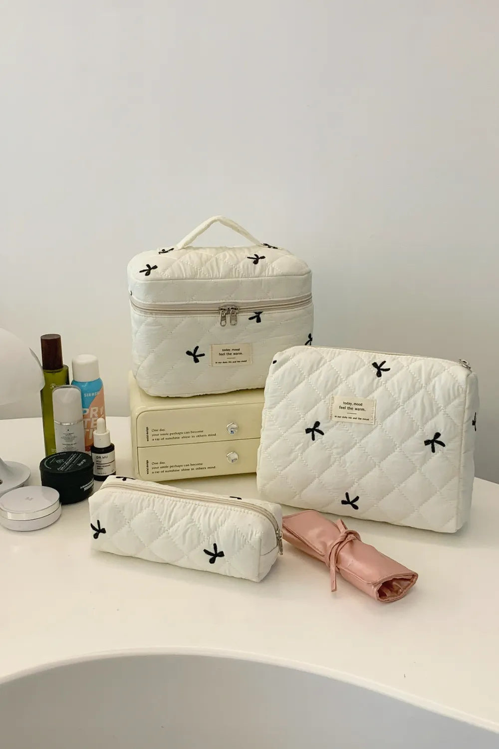 Beige quilted storage set with bow print plus blush pink mini pouch, all zippered