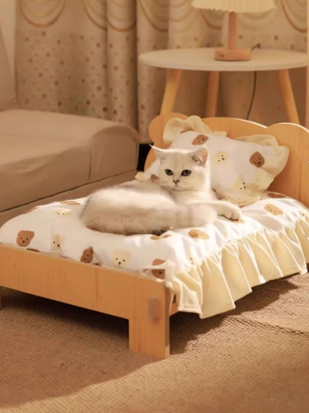 Wooden pet bed with bear-pattern bedding and frilled edges, cat lying near the back.