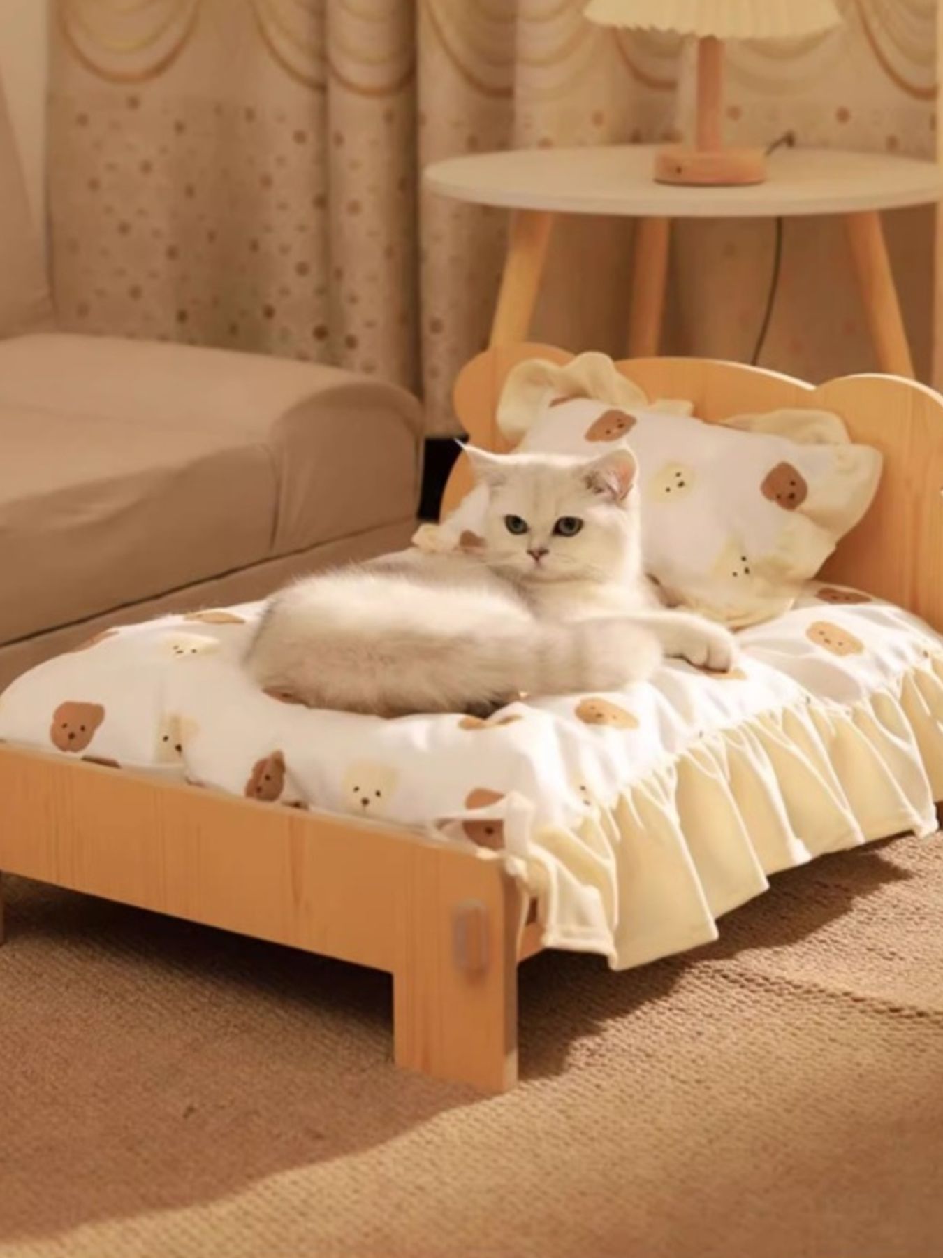 Wooden pet bed with bear-pattern bedding and frilled edges, cat lying near the back.