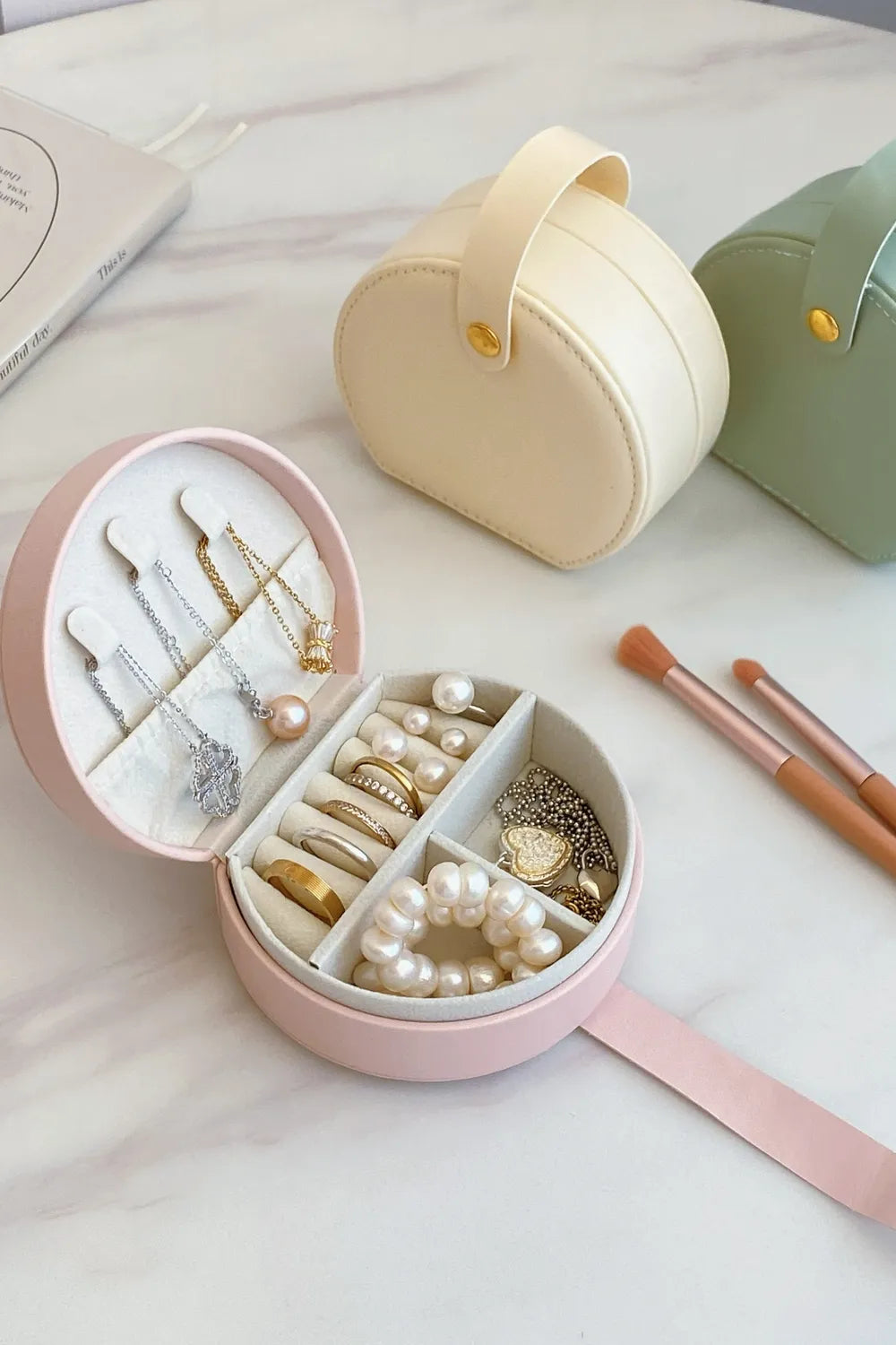 Blush pink PU leather jewelry box open, pearl necklace and ring slots inside