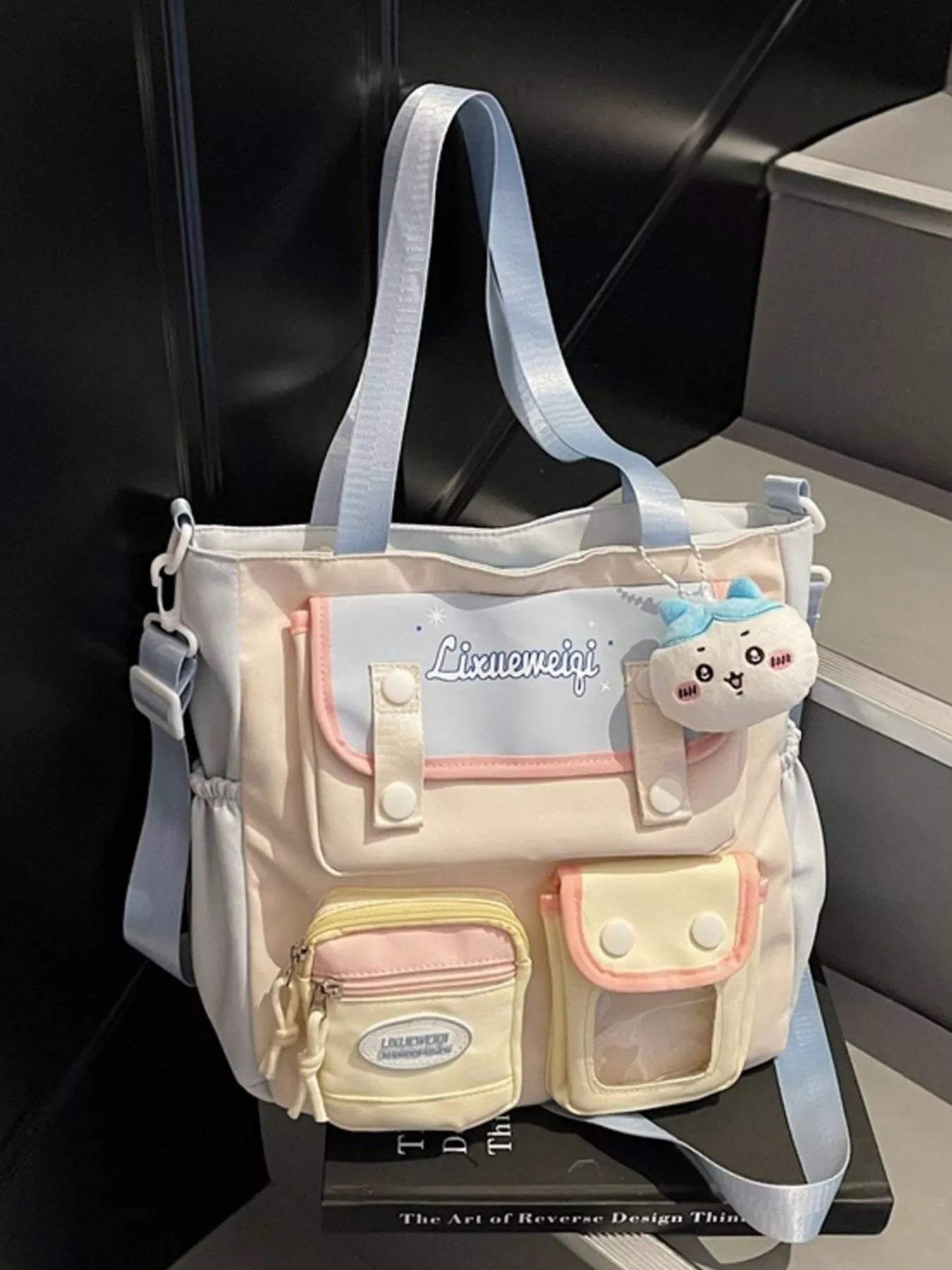 Multi-pocket shoulder bag front view with pastel blue straps, plush charm, and pocket panels