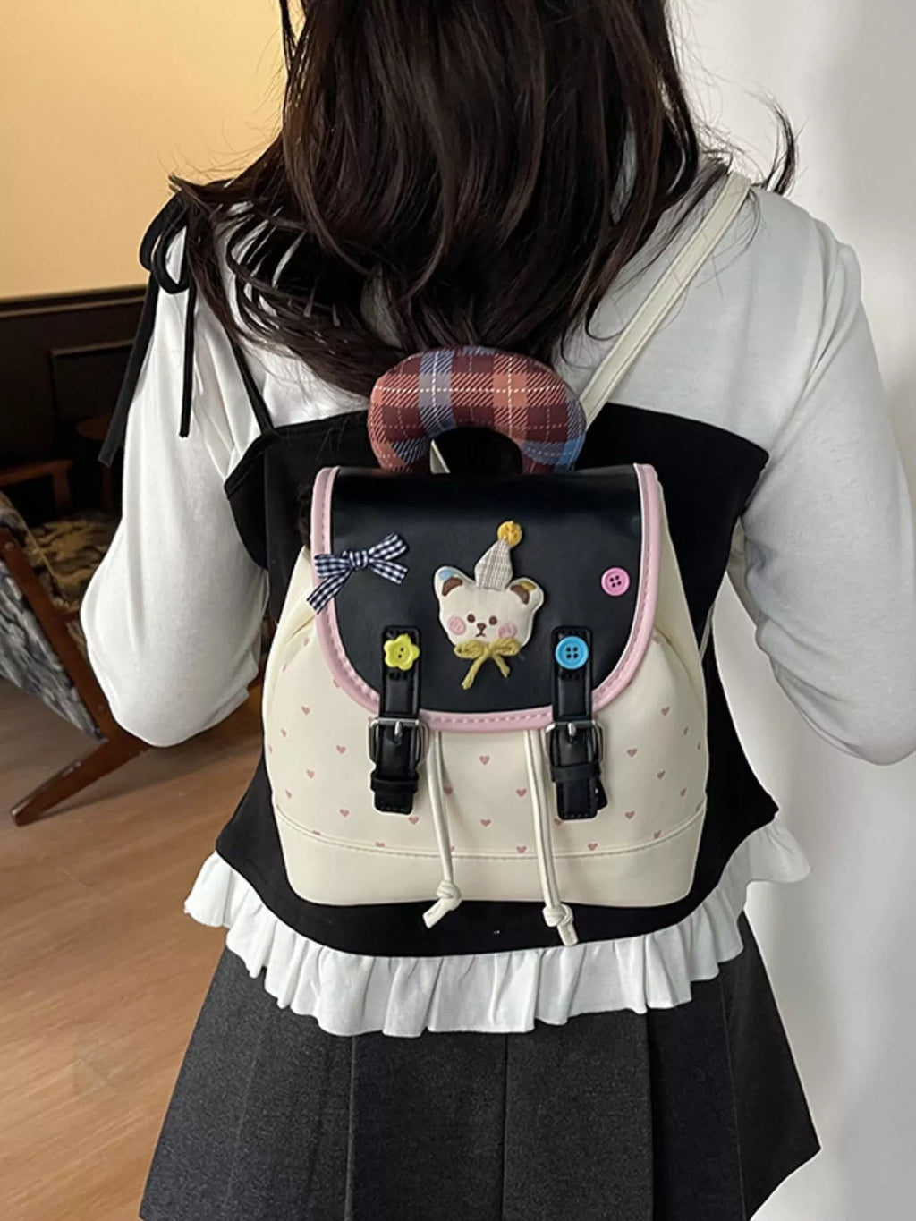 Beige cartoon bear backpack on model: heart pattern body, bear face patch, pink trim