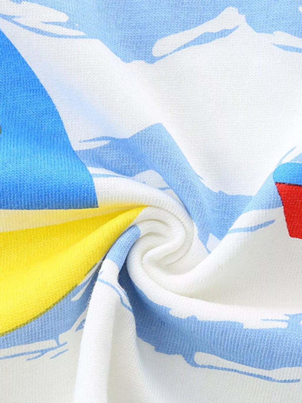 Woven fabric detail of white tee with blue ocean-wave pattern and bright yellow graphic