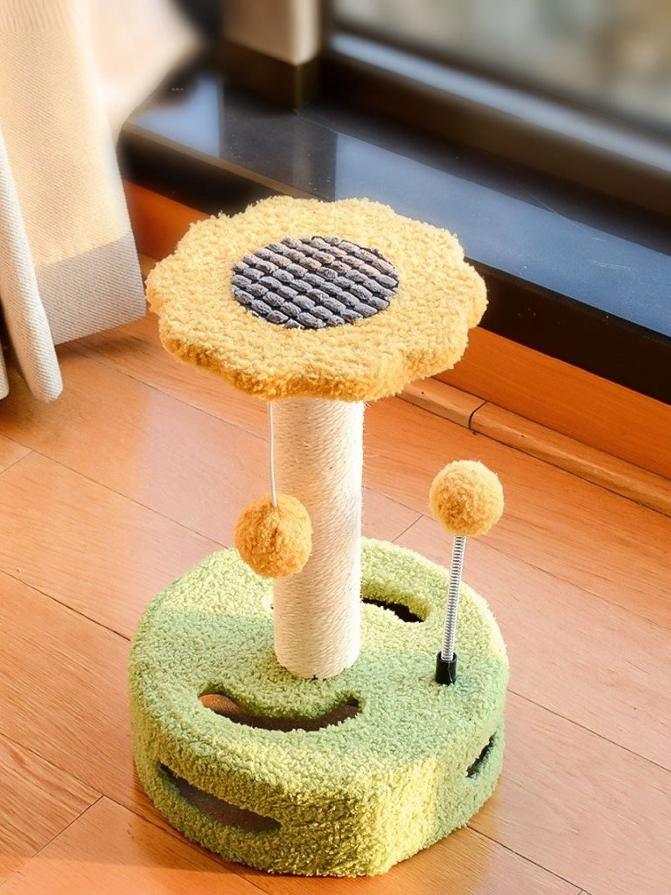 Cat scratching post with dangling balls in yellow top and green base, with round fabric pads