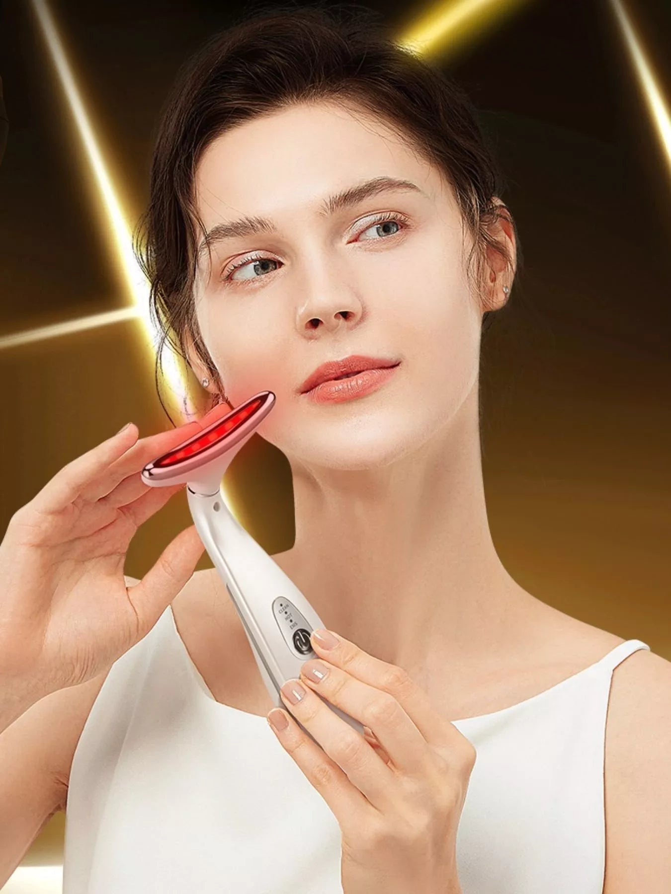 White facial massager held near cheek, red light ring visible on top