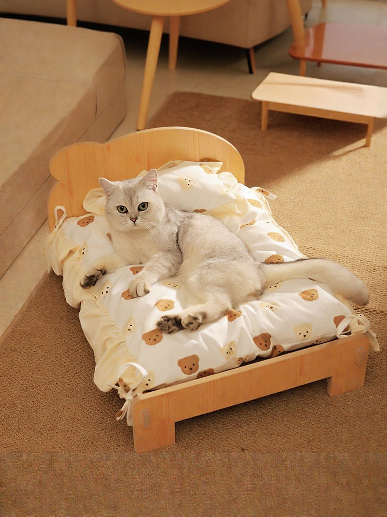 Wooden pet bed with raised sides and white bear-pattern bedding, cat resting inside.