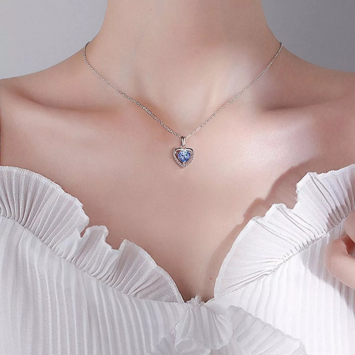Heart zircon necklace on model: silver chain with small blue heart pendant