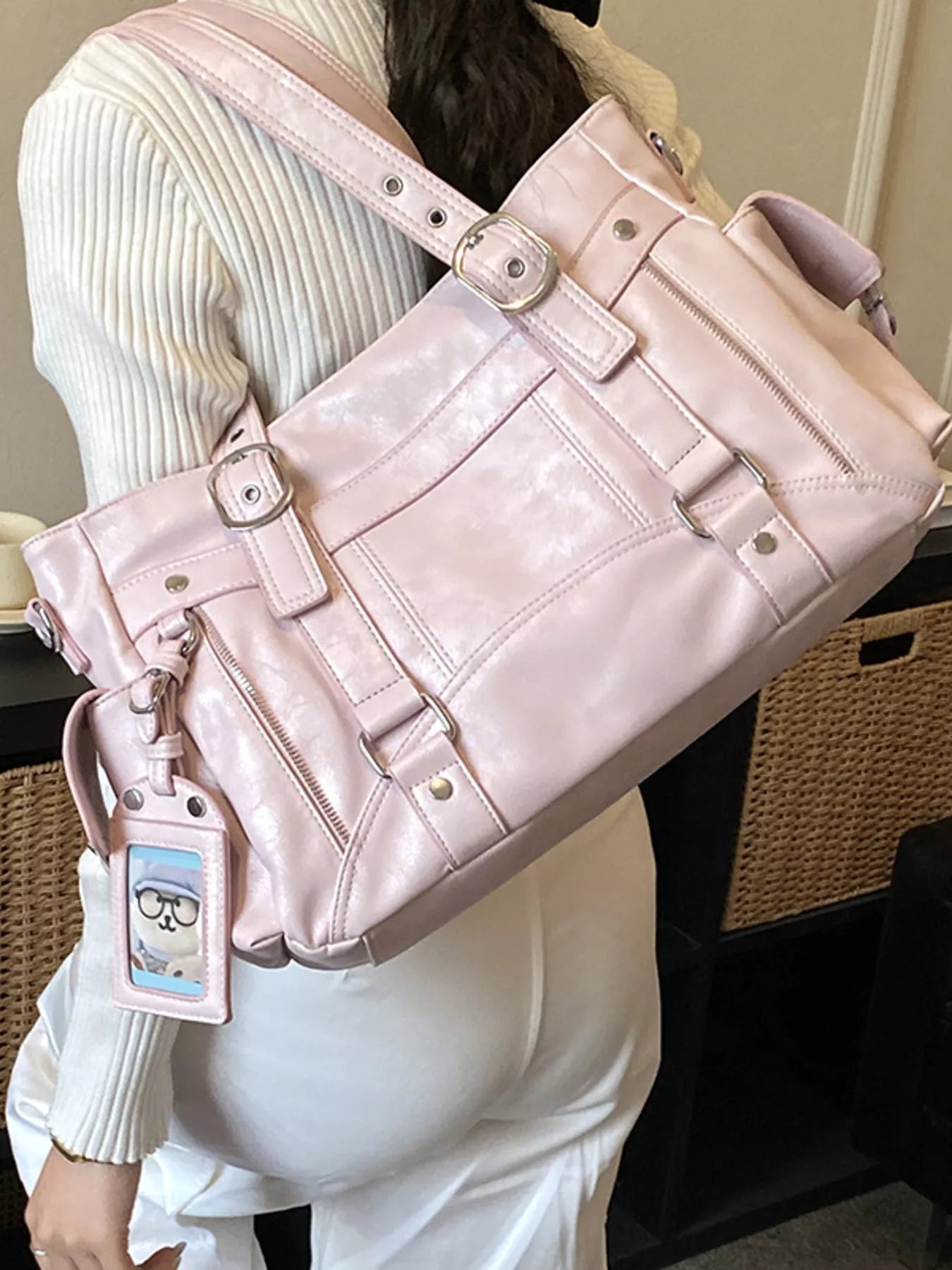 Pink shoulder bag worn over shoulder, buckled straps with zip-front pockets