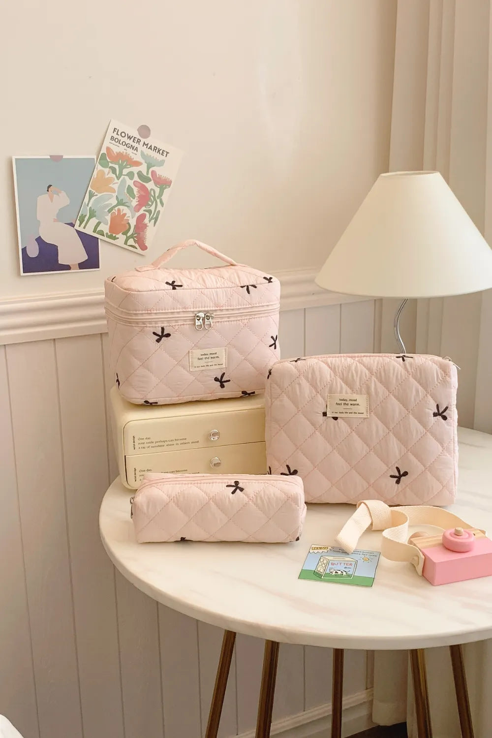 Blush pink quilted 3-piece storage bag set with bow pattern and zip closures.