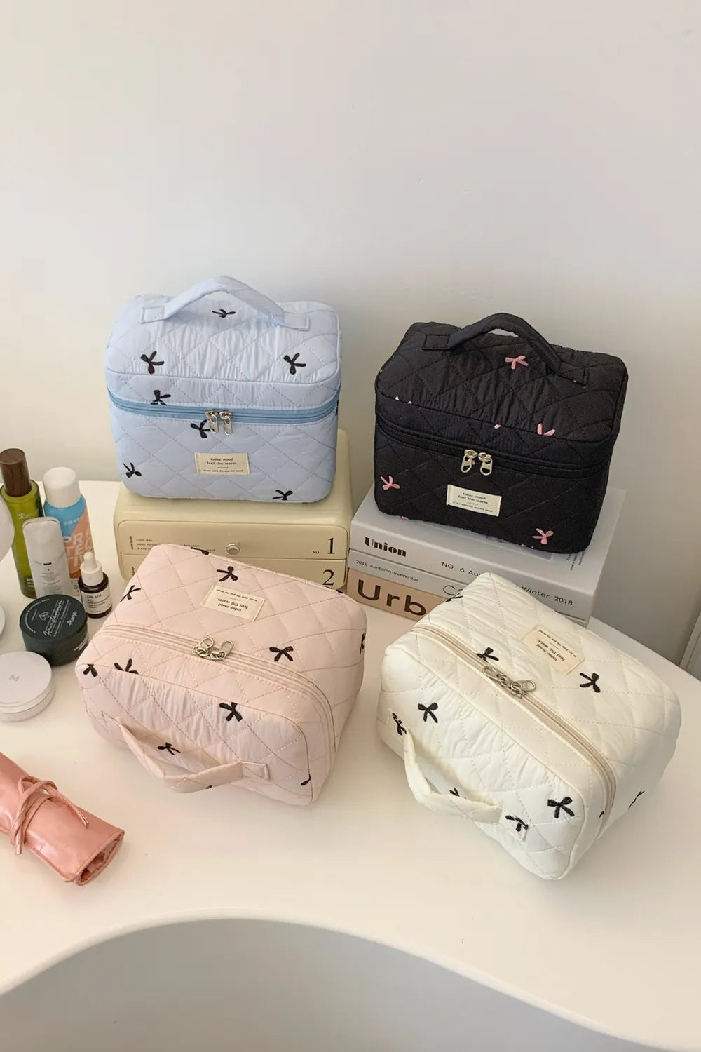 Quilted storage bag set display in light blue, black, blush pink, and white with bows